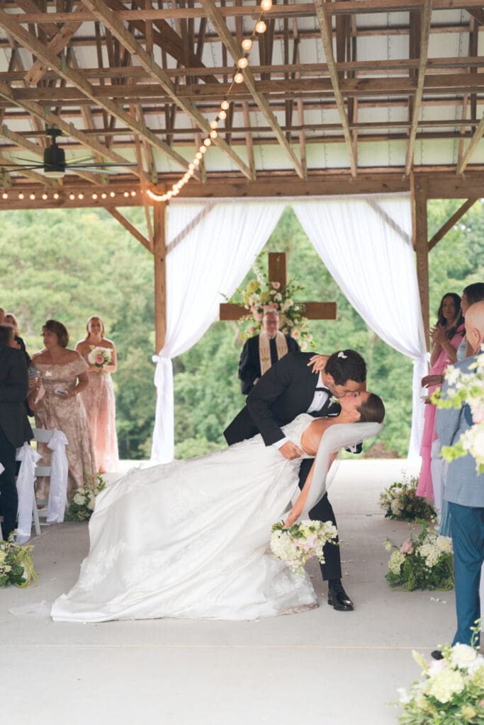 A bride and groom kissing at the end of the aisle