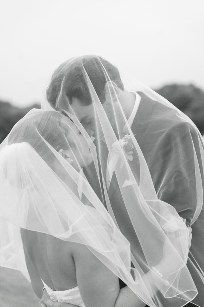 A bride and groom embracing each other underneath her veil