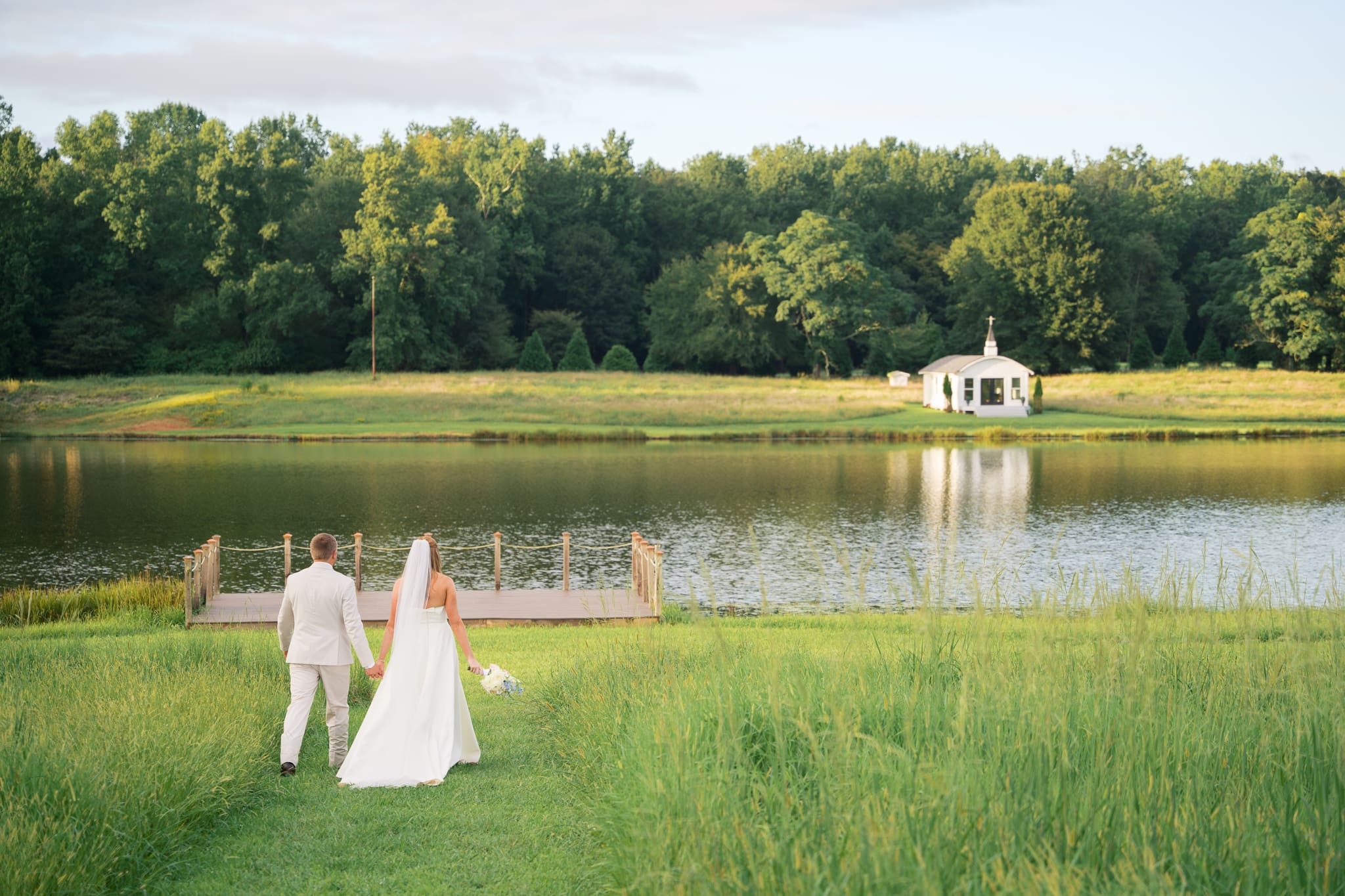 Newlyweds walking during sunset by a lake