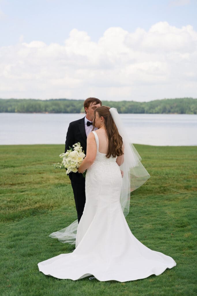 a bride holding her bouquet standing in front of the groom