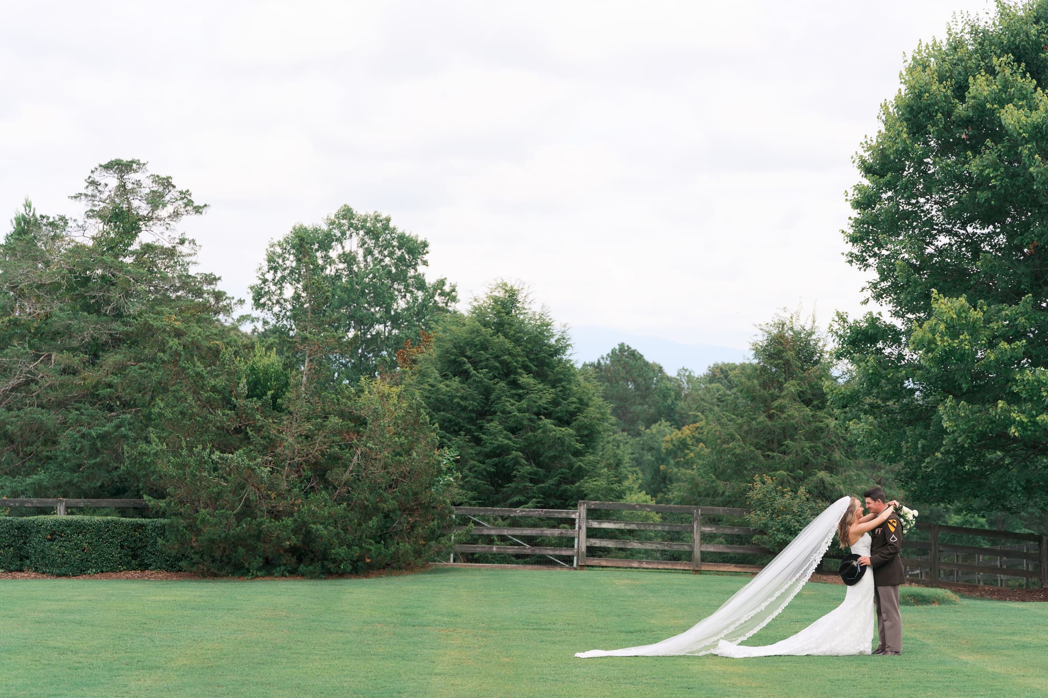 a couple kissing surrounded by green summer foliage on Walnut Hill Farms on their wedding day