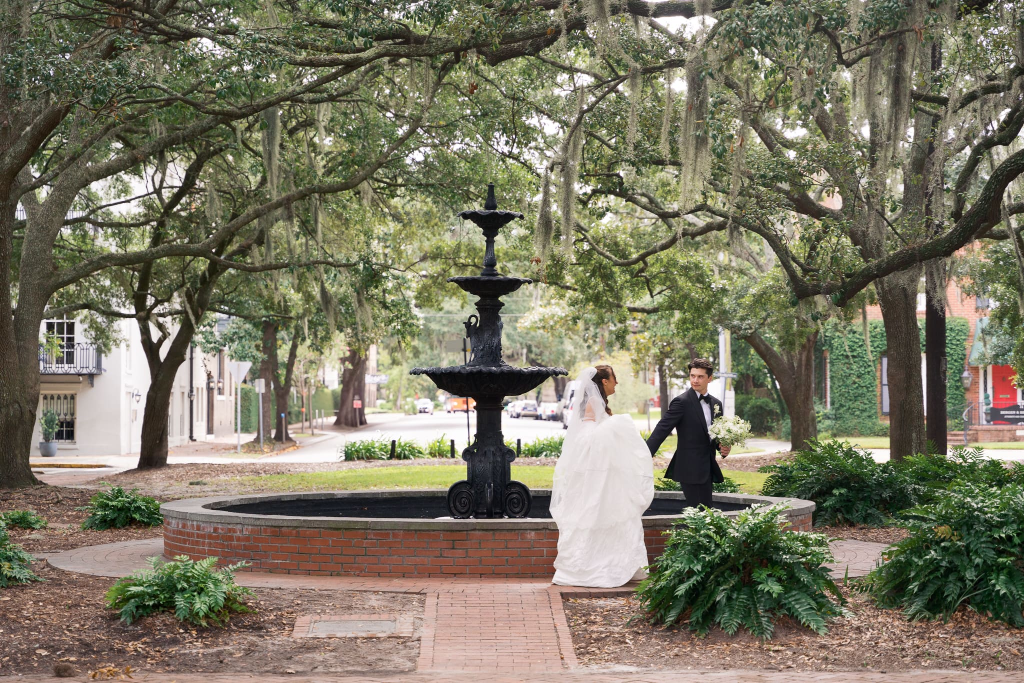 a groom leading his bride underneath the mossy trees in Savannah, Georgia